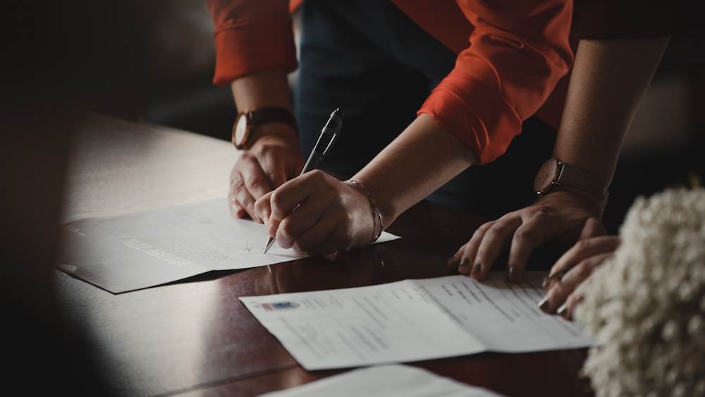 A woman signs a contract after learning about the qui tam false claims act