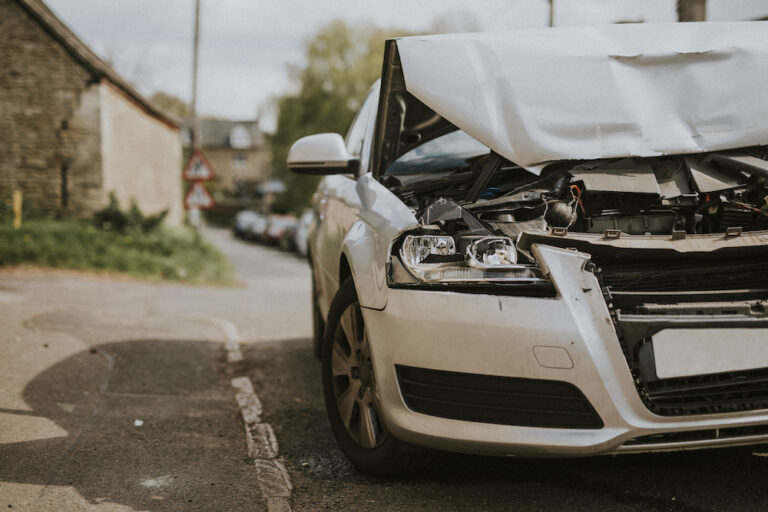 A wrecked car parked on a street after an automobile collision.