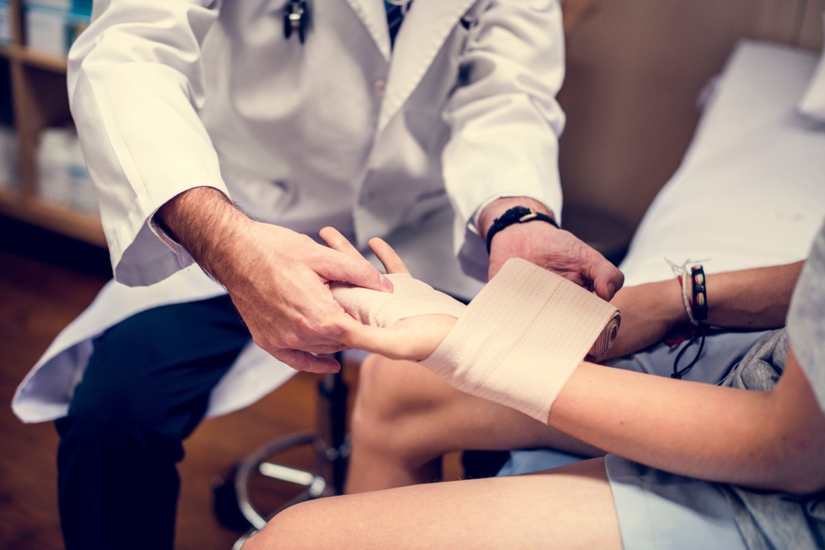 A medical professional wraps a patient's wrist and palm after an injury.